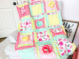 Floral baby pink crib bedding featuring a handmade baby girl rag quilt in shades of yellow, mint green, and pink. This soft, cozy baby blanket is perfect for a baby girl&#39;s nursery, comfortable and colorful, cheerful design. For cribs or throw decor